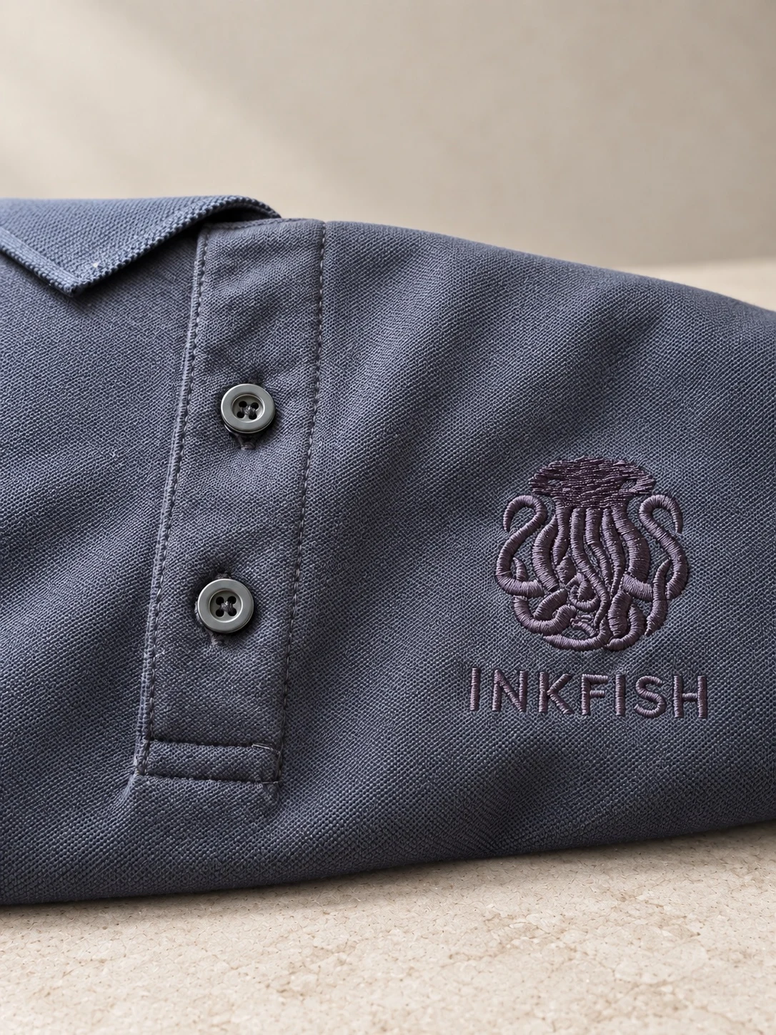 Polo gris con emblema y nombre de Inkfish bordados