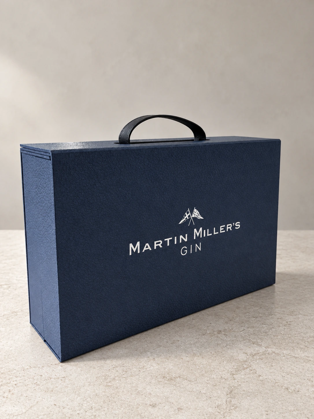 Maletín cerrado azul con asa negra y el logotipo de Martin Miller’s Gin